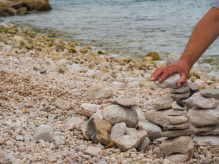 Man's hand holding stone and building zen stones
