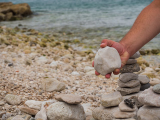 Man's hand holding stone and building zen stones