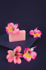 Handmade soaps and flowers on black background. Skin care concept. Beauty. Natural Soap making. Soap bars closeup. 