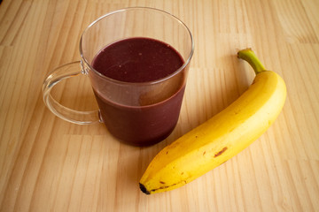 ガラスのマグカップのアサイードリンクとバナナ1本 a glass cup of açaí drink and a banana 1