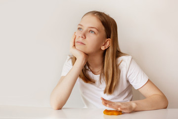 Fototapeta premium A pretty girl holds a slime with her hand and looks thoughtfully into the distance