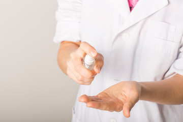 closeup of a caucasian doctor woman, in a white coat, disinfecting his hands with hand sanitizer from a bottle