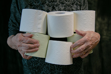 Old woman holds toilet rolls Panic due to covid-19 coronavirus. People buy basic necessities in bulk at supermarkets. Panic stop concept