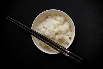 Bowl with rice and chopsticks over the table