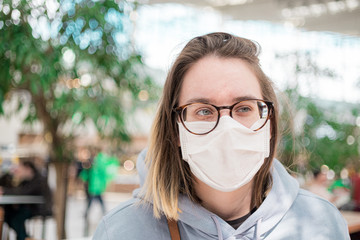 Woman in medical face mask siting in mall close up portrait. Corona virus infection protection
