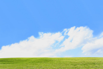 雲と青空を背景にした緑の丘。背景用素材