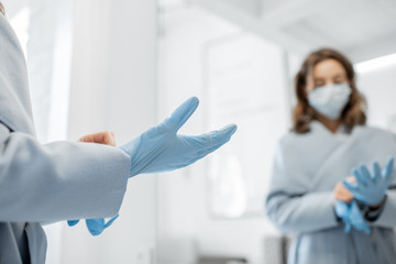 Woman in medical mask wearing gloves while going outside, protecting from the virus during an...