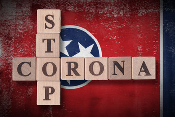 Obraz premium Flag of the state of Tennessee with wooden cubes spelling STOP CORONA on it. 2019 - 2020 Novel Coronavirus (2019-nCoV) concept art, for an outbreak occurs in Tennessee, US.
