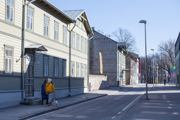 Couple of women walking a small dog in a hip neighborhood, Kalamaja, Tallinn on a sunny spring morning