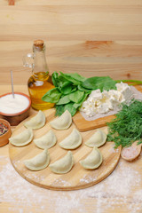 Dumplings on a wooden board with vegetables and cottage cheese
