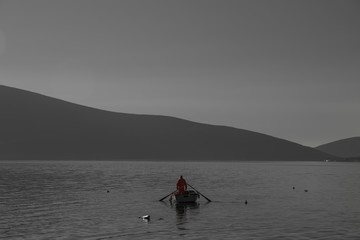 fisherman in a red jacket on a background of black and white lake