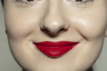Naklejka premium Calm, delighted. Close-up shoot of female mouth with bright red gloss lips make-up and well kept cheeks skin. Cosmetology, medicine, dentistry and beauty care, emotions and facial expression concept.