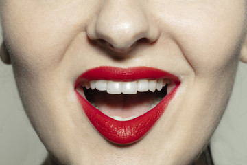 Smiling with teeth. Close-up shoot of female mouth with bright red gloss lips make-up and well kept chicks skin. Cosmetology, medicine, dentistry and beauty care, emotions and facial expression
