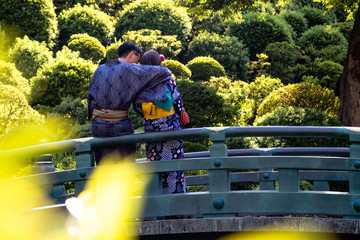 A young couple wearing kimonos cuddling on a bridge