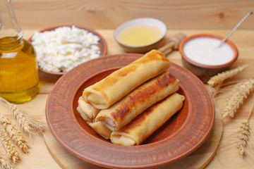 Crepes on a wooden board with cottage cheese