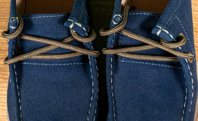 Closeup top view photography of details of casual blue leather mocassins with brown shoelaces.