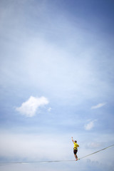 tightrope walker on a mountain with blue sky and clouds