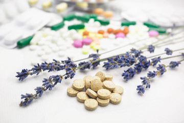 The concept of pills for treatment. Multi-colored pills on a white isolate. Hope for cure, hope for medicine. Daily dose. Herbal natural pills against chemistry. Lavender twigs.