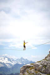 tightrope walker on a mountain with blue sky and clouds