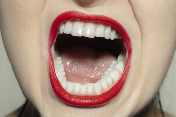 Angry screaming. Close-up shoot of female mouth with bright red gloss lips make-up and well kept...