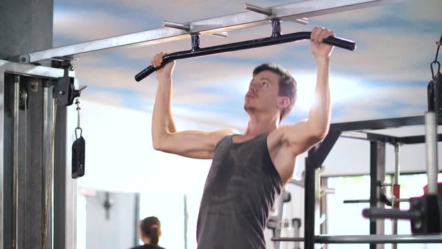 Young caucasian man gym beginner doing pull up exercise in the gym.
