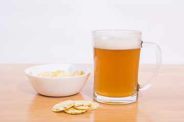 Beer mug full of beer and chips in a white plate on the white background 