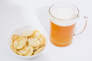 Beer mug full of beer and chips in a white plate on the white background 