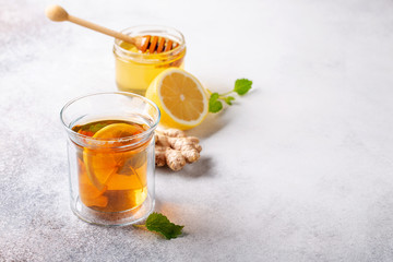 Cup of hot tea with ginger, lemon,mint and honey on concrete background.