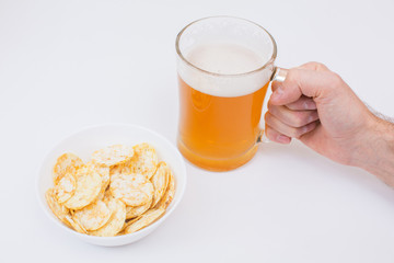 Beer mug full of beer and chips in a white plate on the white background 