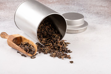 Oolong tea leaves in metal container on concrete background. Copy space.