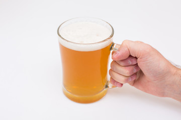 Man holding beer mug full of beer on wooden table on white background
