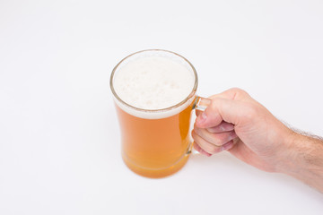 Man holding beer mug full of beer on wooden table on white background
