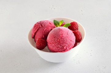 Raspberry ice cream scoop with fresh raspberries in bowl