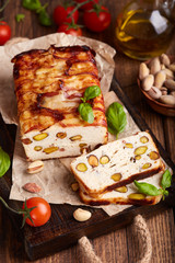 Meatloaf from Chicken breast filet with pistachio nuts, covered with slices of bacon, decorated with basil leaves. Delicious homemade appetizer.