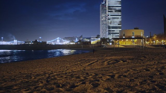Playa de barcelona por la noche con edificios iluminados