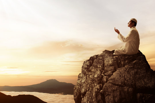 Religious asian muslim man praying on top of mountain