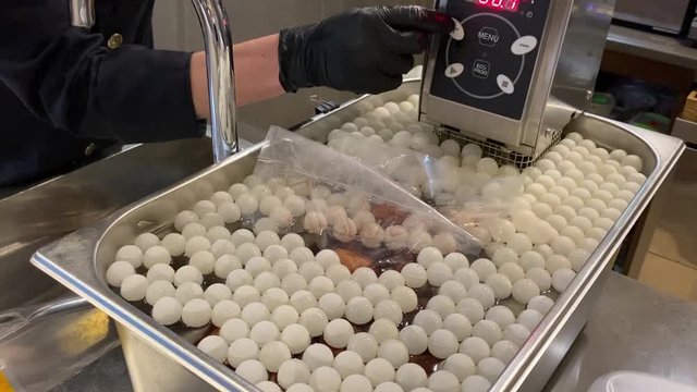 Chef immerses in equipment hermetically packed in a bag of pear soaked in wine sauce.