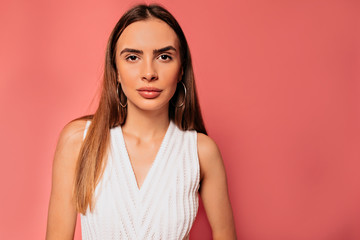 Fototapeta premium Close up portrait of attractive pretty woman with long hair wearing white t-shirt posing over pink background