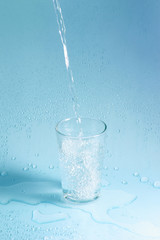 pouring water in glass on pastel background
