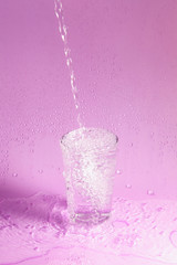 Fototapeta na wymiar pouring water in glass on pastel background