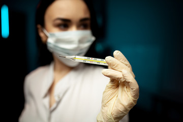 Female doctor with a doctor mask and a thermometer. Breathing medical respiratory mask. Virus protection.