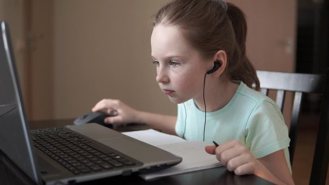Girl with earphones learning online on computer, communicate with teacher, writing, distance education due quarantine time.