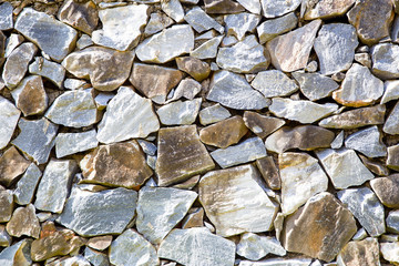 Fragment of a stone wall of stones of different, irregular shapes. Horizontal.