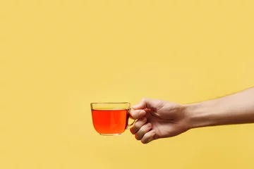 Fototapete Rund Tee hand holding a glass tea mug on a yellow background.  © Алексей Коза