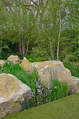 Unusual large rocks used in an urban garden design with inserted flowers and plants