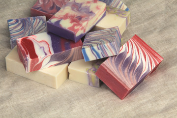 Pile of cold process design soaps on display on linen backdrop