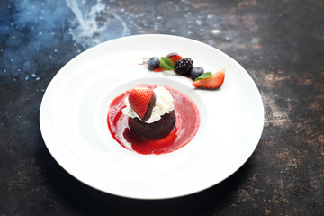 Chocolate fondant with whipped cream served with raspberry sauce.