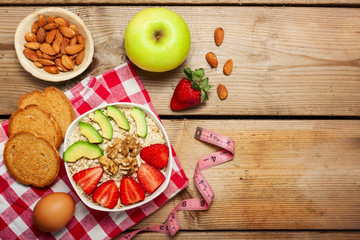 Healthy breakfast made of oats  with nuts, avocado and fresh strawberries  and fruits  on wooden  table,copy space in the middle