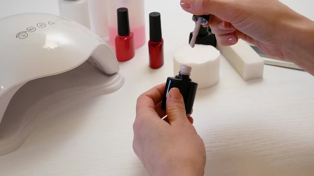 The girl opened a jar with beige shellac