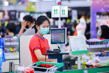 Cashier or supermarket staff in medical protective mask working at supermarket. © pixfly
